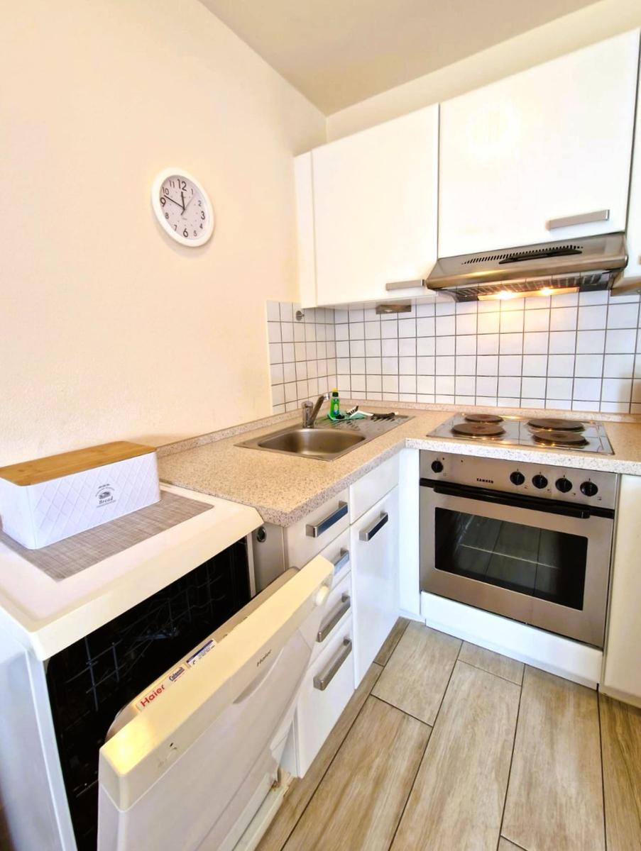 Küche mit weißen Schränken, Edelstahlherd und Spüle.