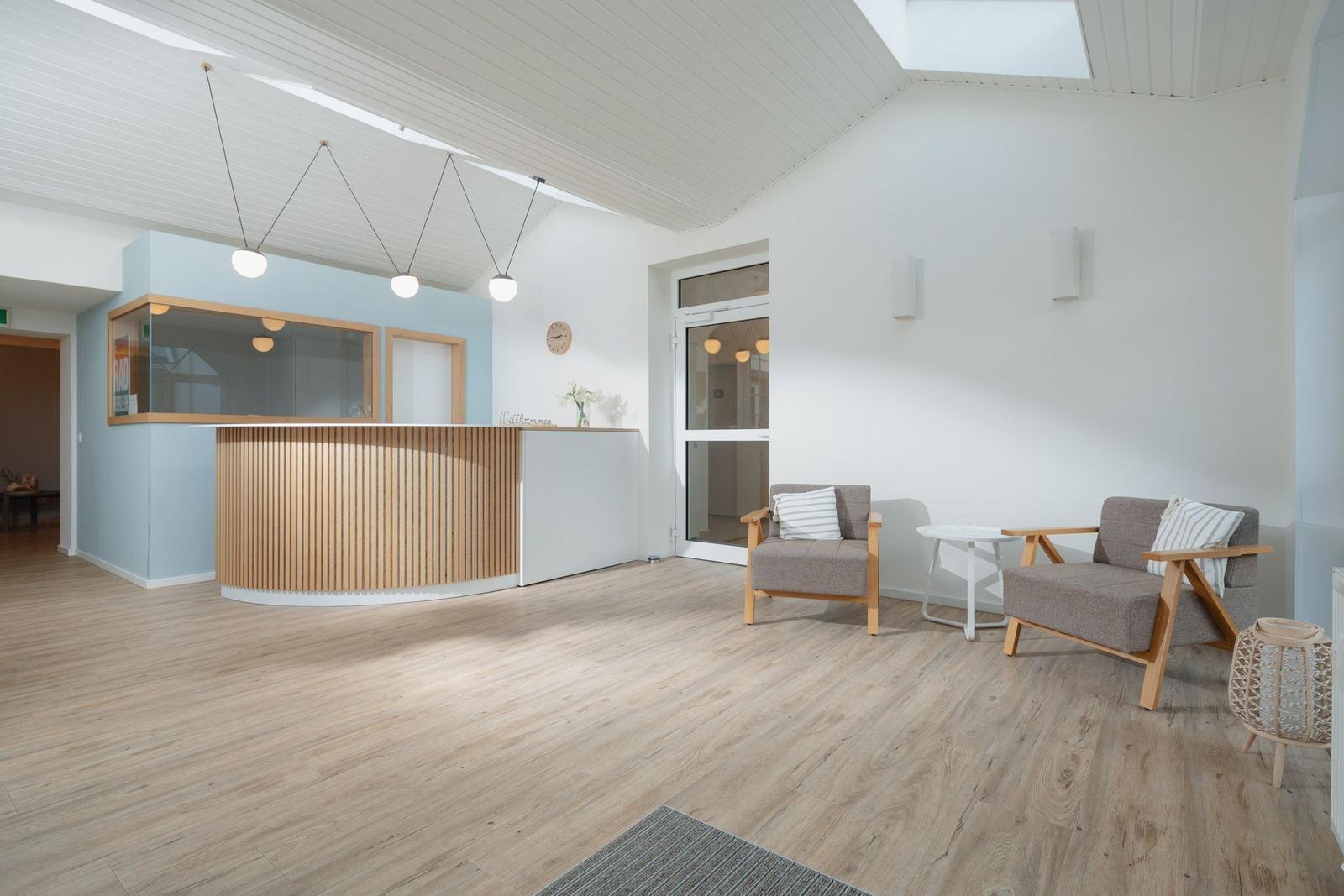 Rezeption mit Holzfront, zwei Sessel und Tisch im Eingangsbereich.