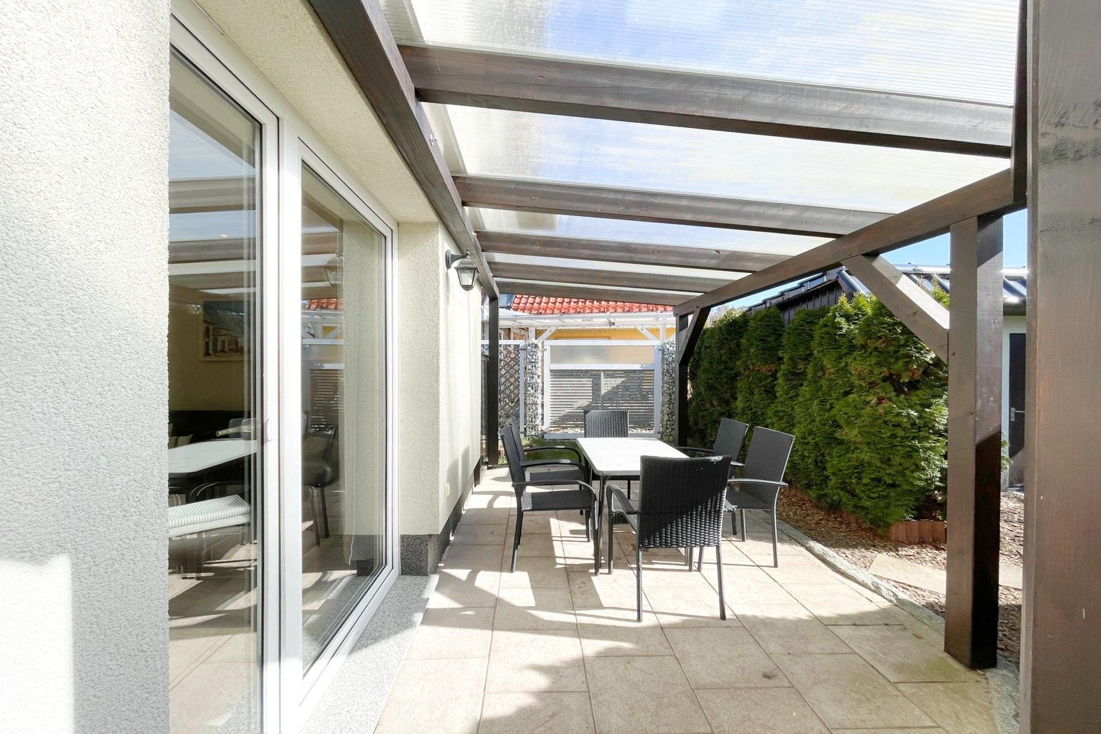 Terrasse mit Tisch und Stühlen unter Dach