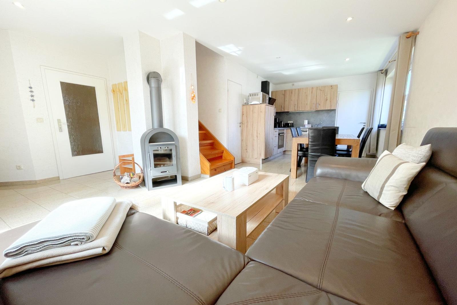 Wohn- und Essbereich mit Holztisch, Sofa und Kaminofen.