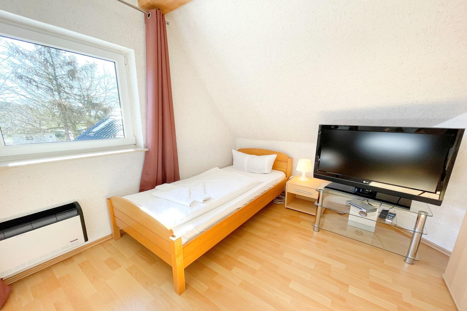 Ein Schlafzimmer mit Bett, Fernseher und Fenster.