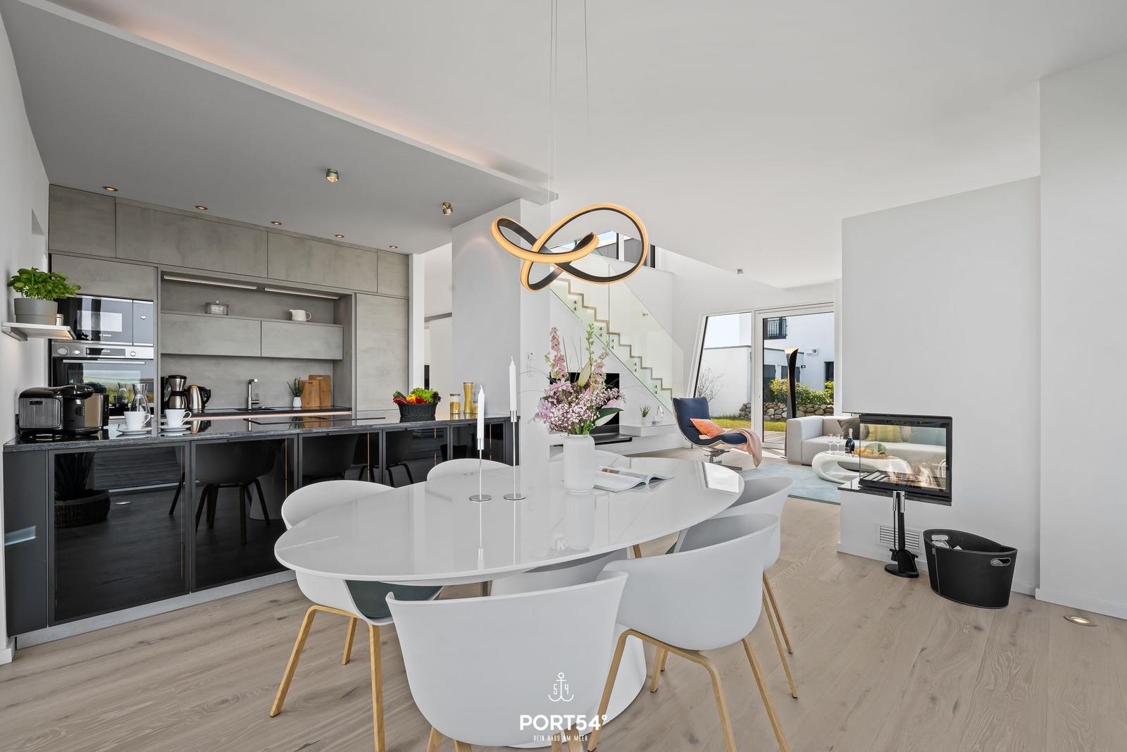 Moderne Küche mit Essbereich und Wohnzimmer mit Kamin und Glasgeländer.