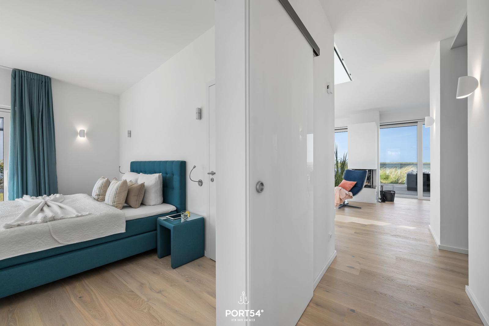 Schlafzimmer mit blauem Bett und Blick auf Terrasse