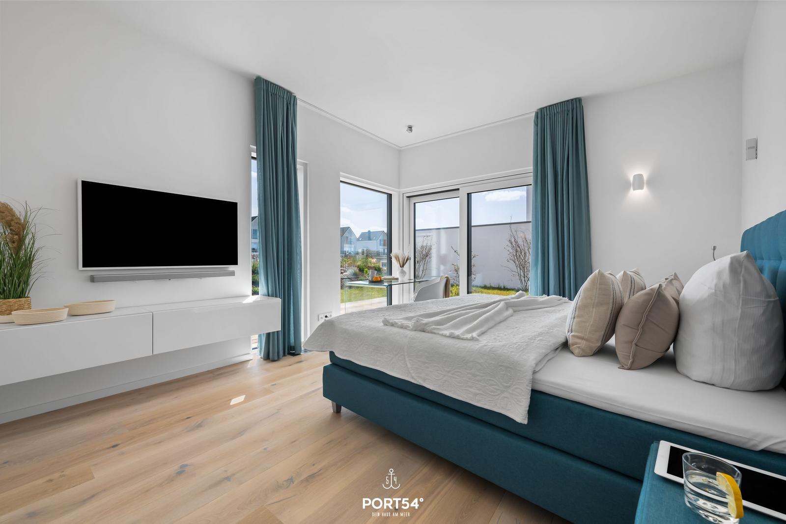 Schlafzimmer mit Bett, TV und Fenster zur Terrasse