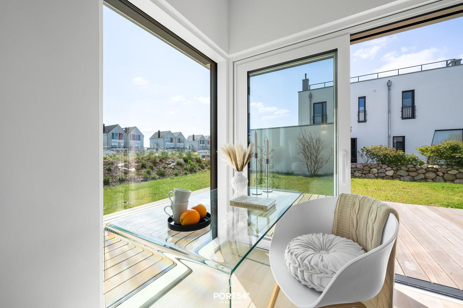 Terrasse mit Sitzgelegenheit und Blick auf Garten und Nachbarhäuser.