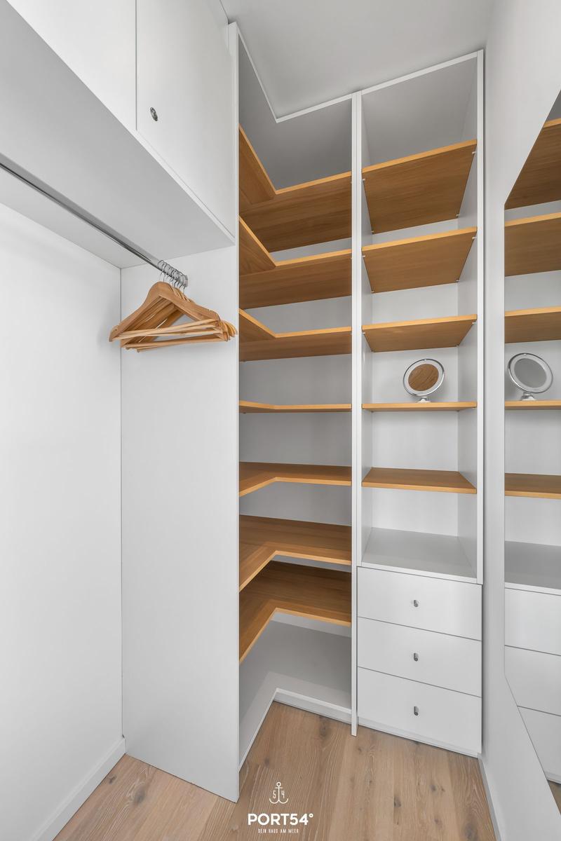 Schrank mit Holzregalen, Kleiderhaken und Schubladen im Schlafzimmer.