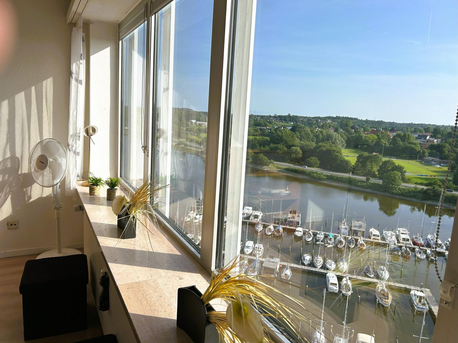 Großes Fenster mit Blick auf Hafen und Grünflächen