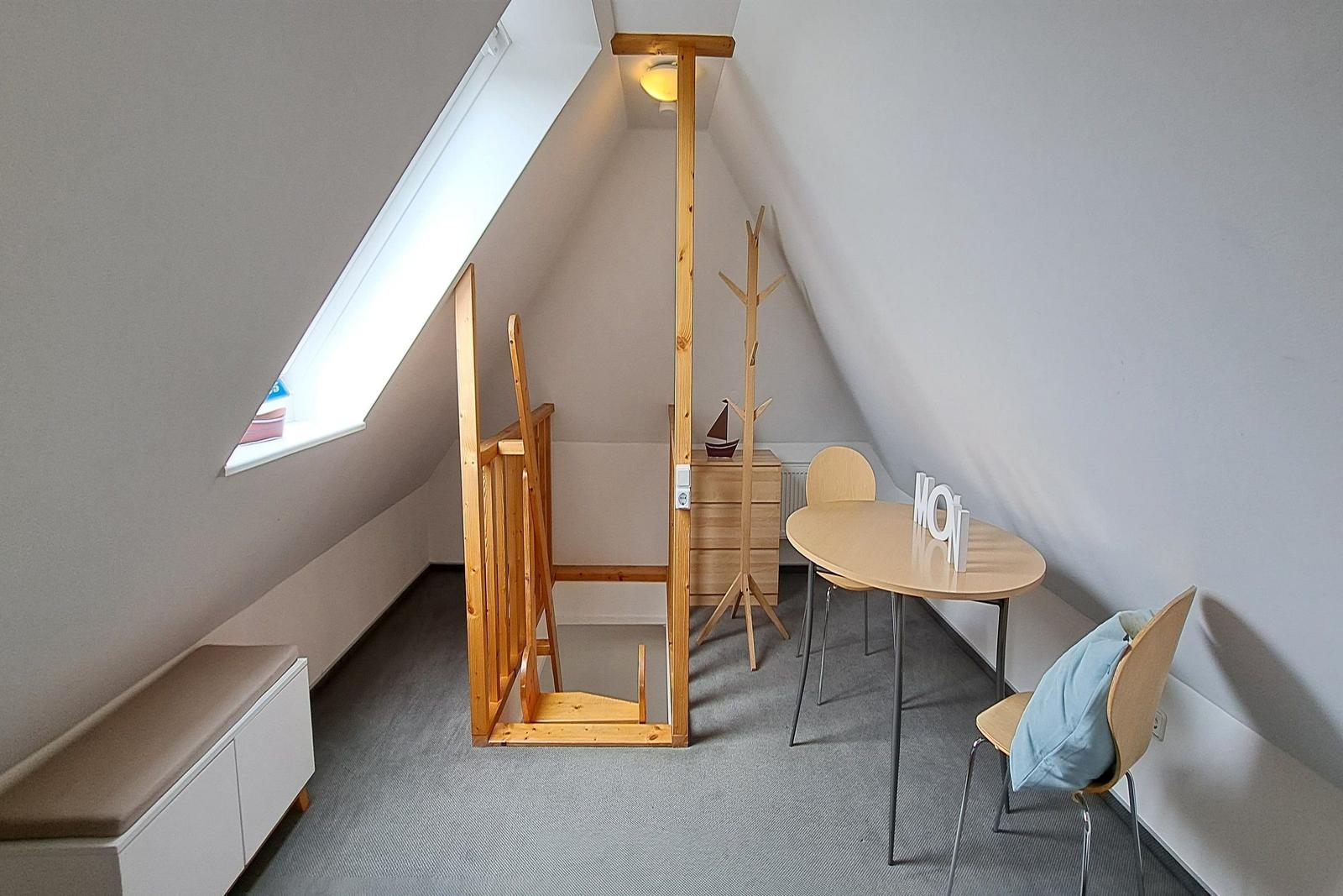 Dachgeschosszimmer mit Tisch, Stühlen und Babybett