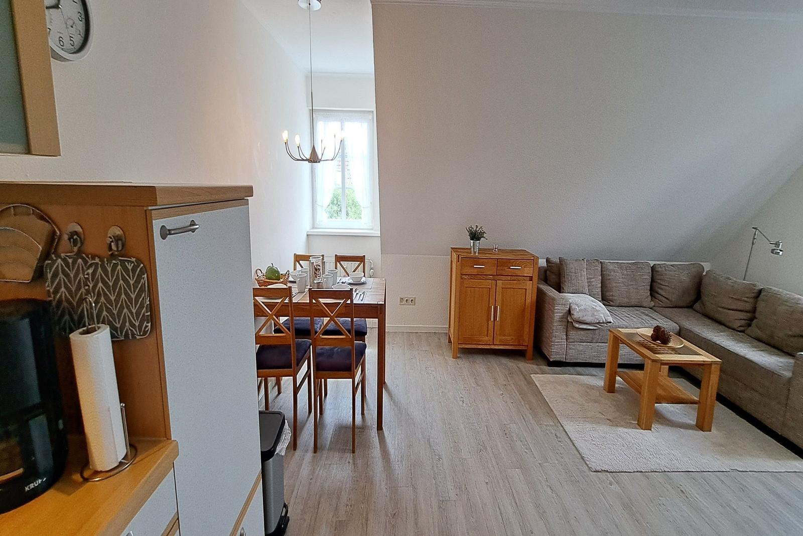 Wohn- und Essbereich mit Sofa, Tisch und Küchenzeile.