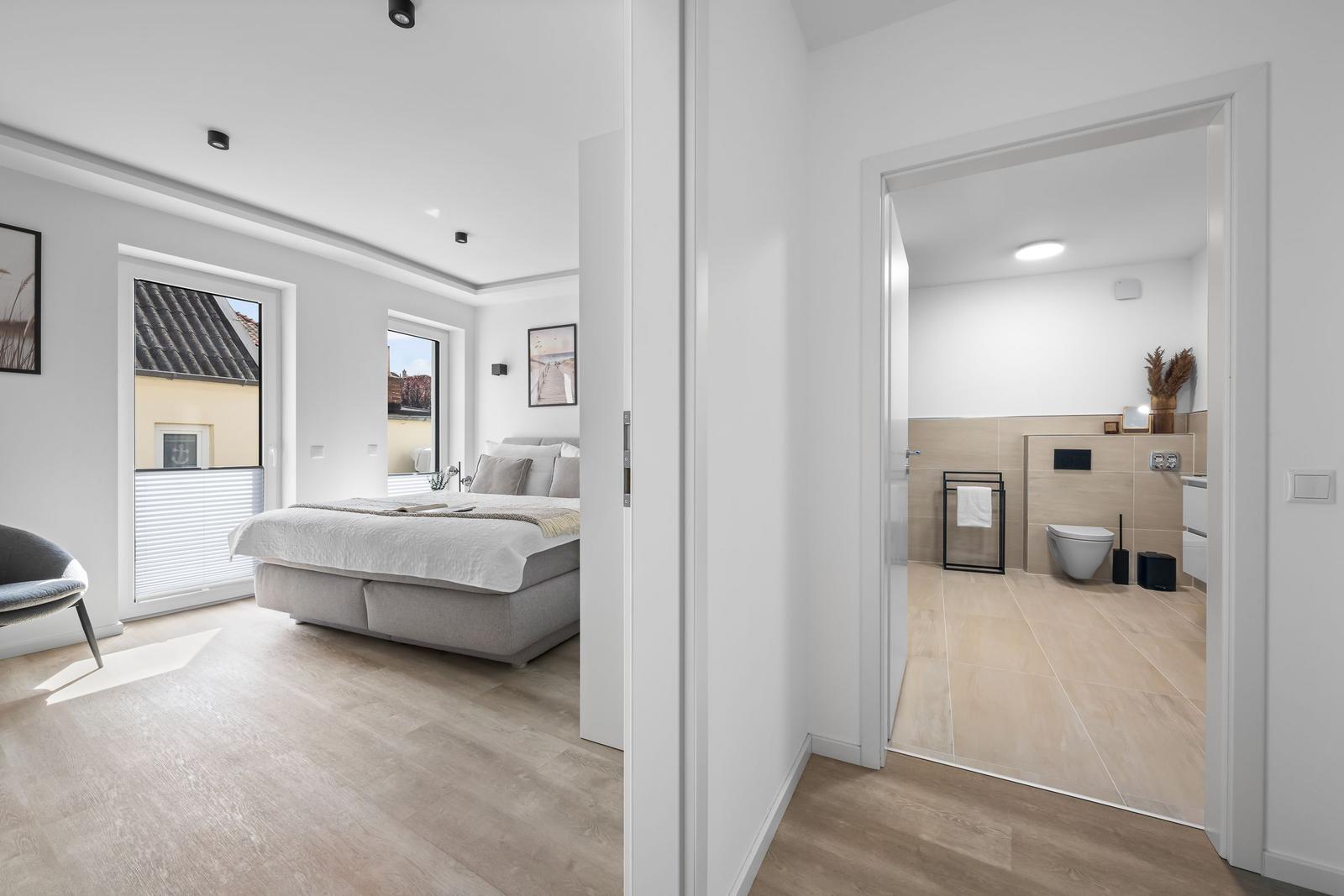 Schlafzimmer mit Blick auf Dach und Bad mit Toilette und Handtuchhalter.