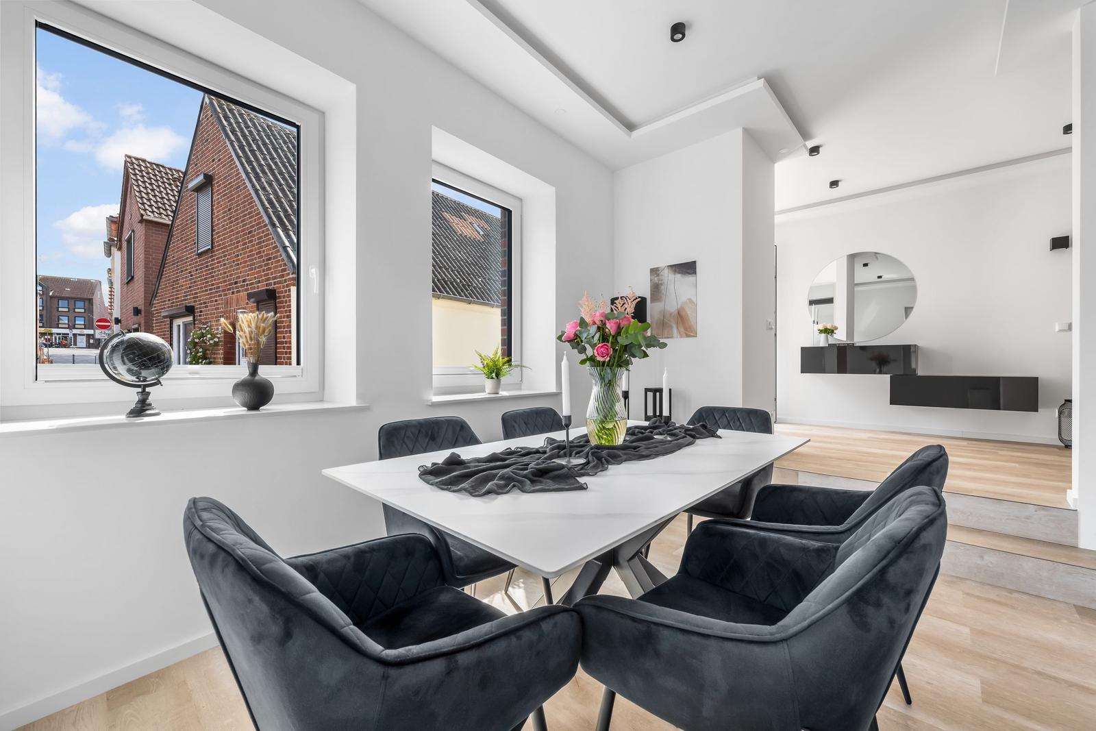 Essbereich mit Tisch und Stühlen, Blick auf Straße und Haus.