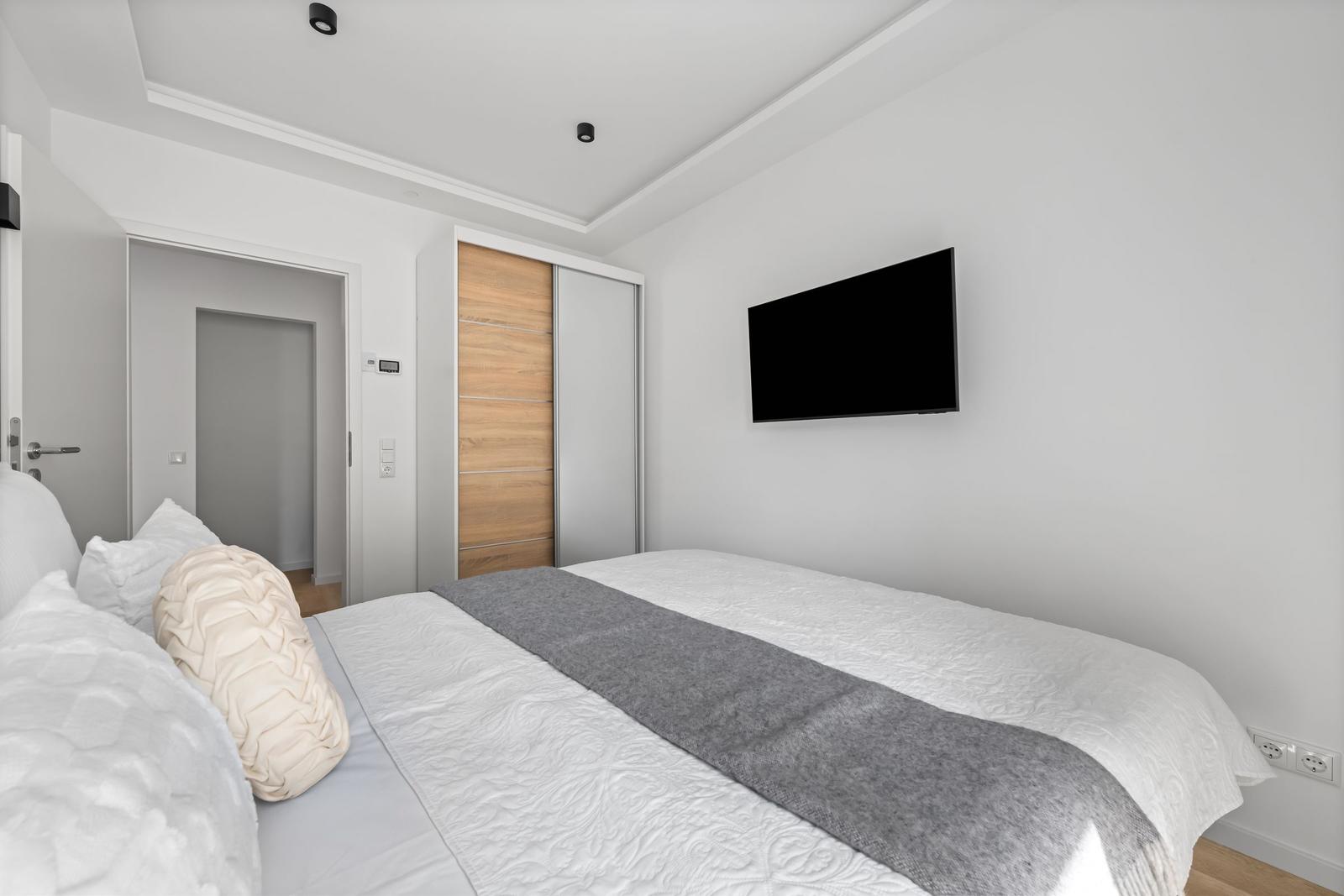 Schlafzimmer mit Bett, Fernseher und Kleiderschrank