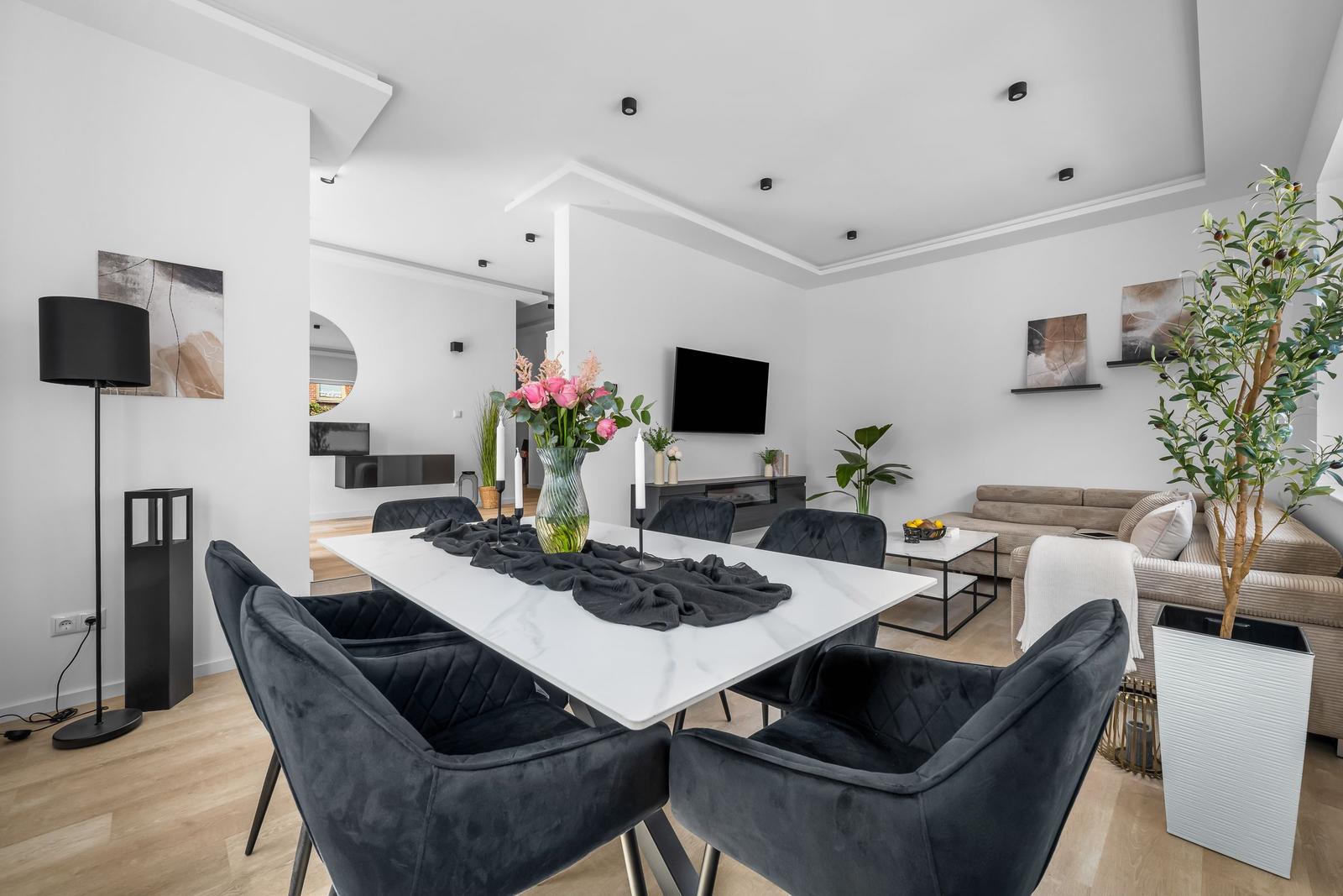 Essbereich mit Esstisch und Stühlen. Wohnzimmer mit Sofa und Fernseher.