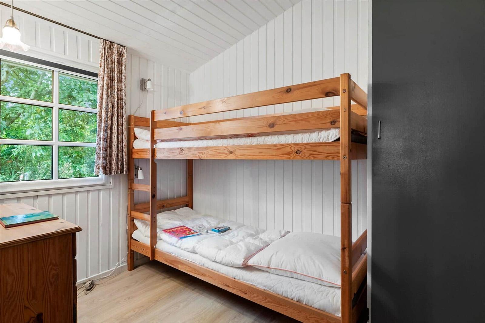 Ein Schlafzimmer mit einem Holzbett, einem Fenster und einem Schrank.
