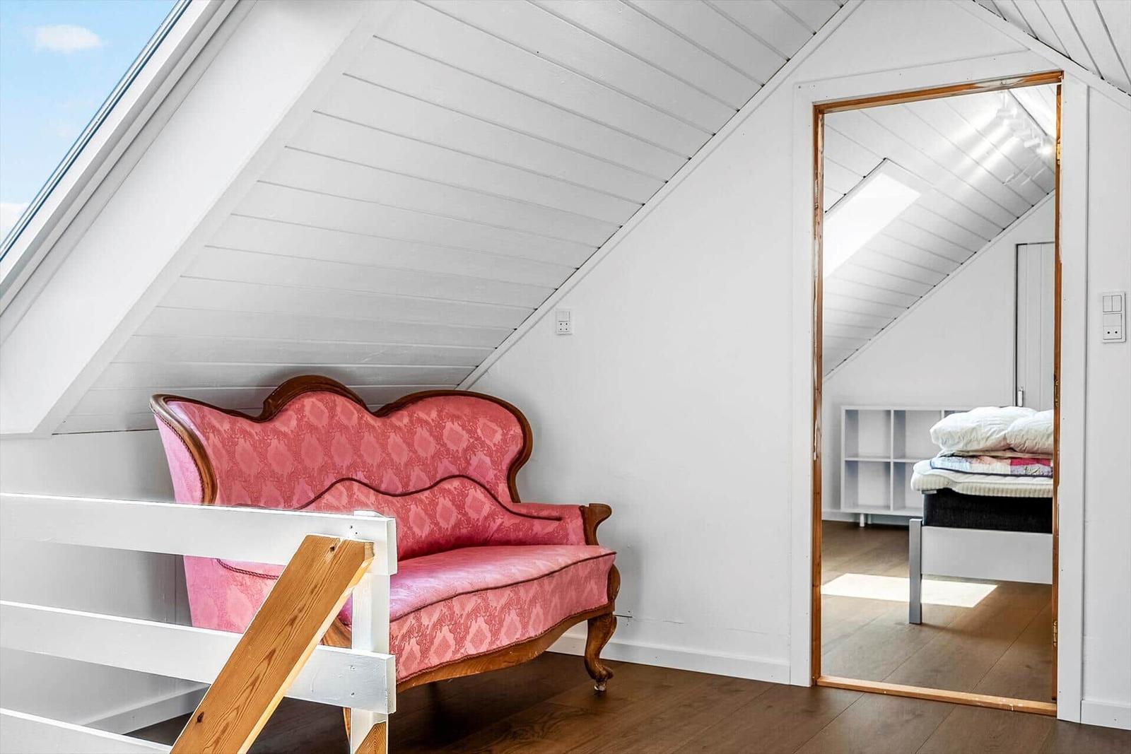 Ein Raum mit einem rosa Sofa und einem Schlafzimmer im Hintergrund.