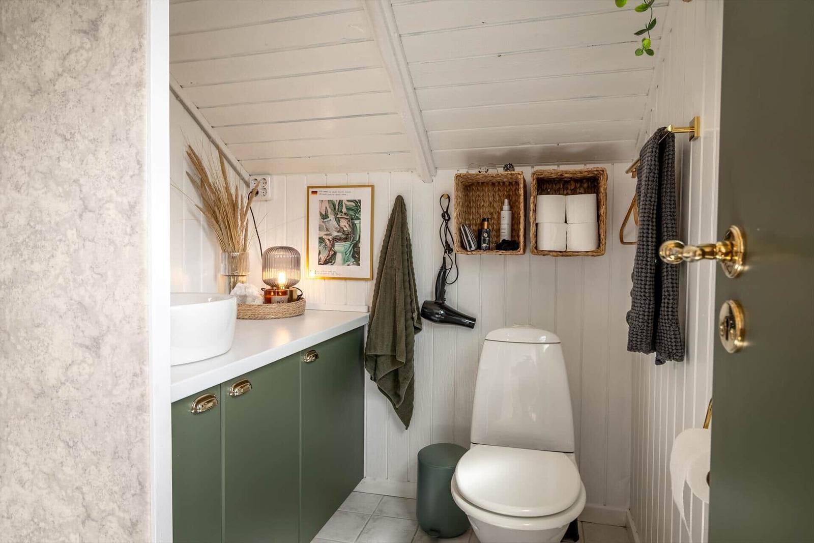 Badezimmer mit Toilette, Waschbecken und Aufbewahrungskörben an der Wand.