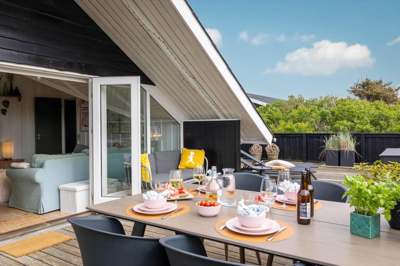 Terrasse mit gedecktem Tisch, Sofa und Blick auf Grünflächen.