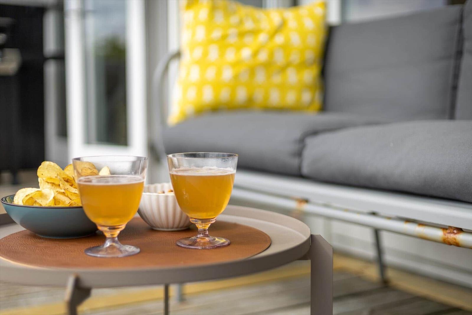 Auf dem Balkon stehen zwei Gläser mit Getränk und eine Schale mit Chips.