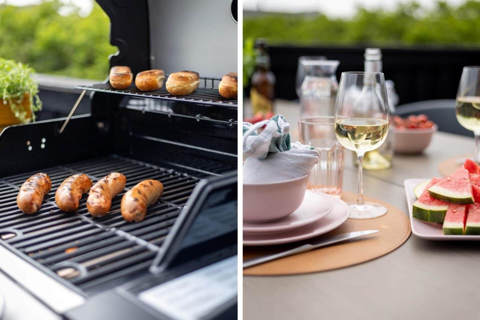 Grill mit Würstchen und Brötchen. Tisch mit Wein, Obst und Geschirr.