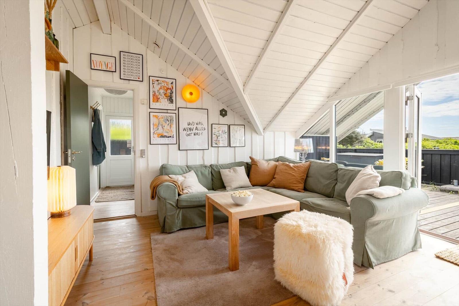 Wohnzimmer mit Sofa, Tisch und Blick auf die Terrasse.