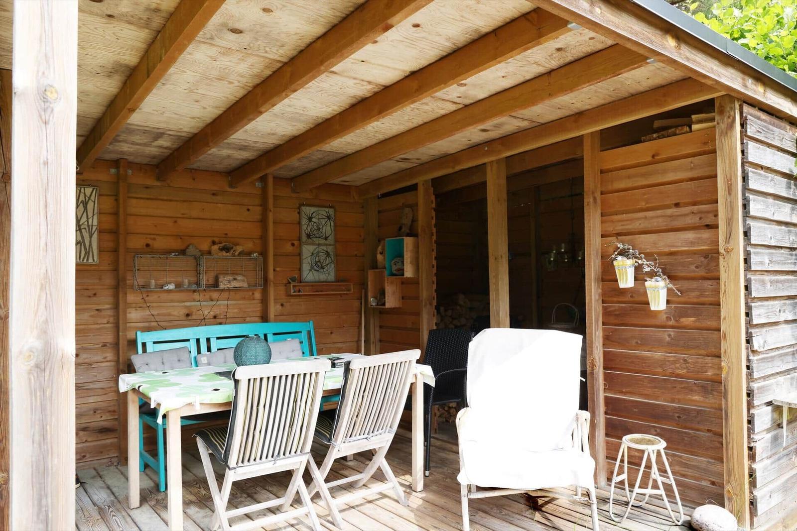 Holzterrasse mit Tisch, Stühlen und Sitzgelegenheiten. Wanddekoration und Holzwände.