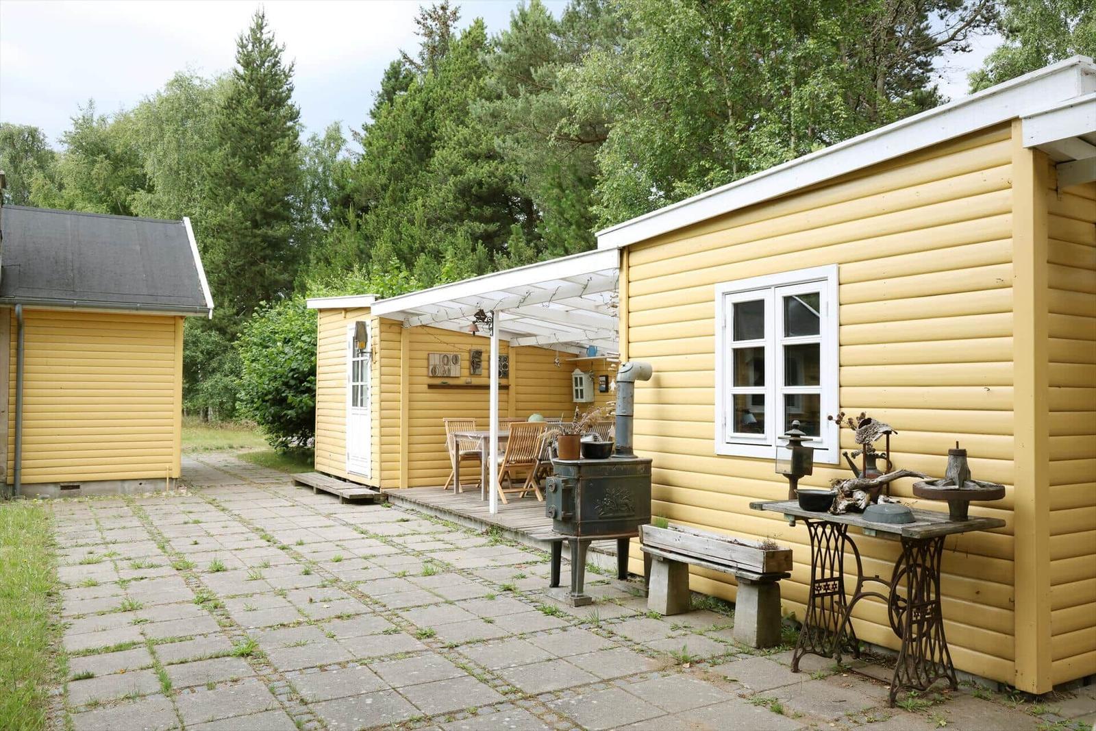 Gelbe Holzhütten mit Terrasse und Grillplatz im Grünen.