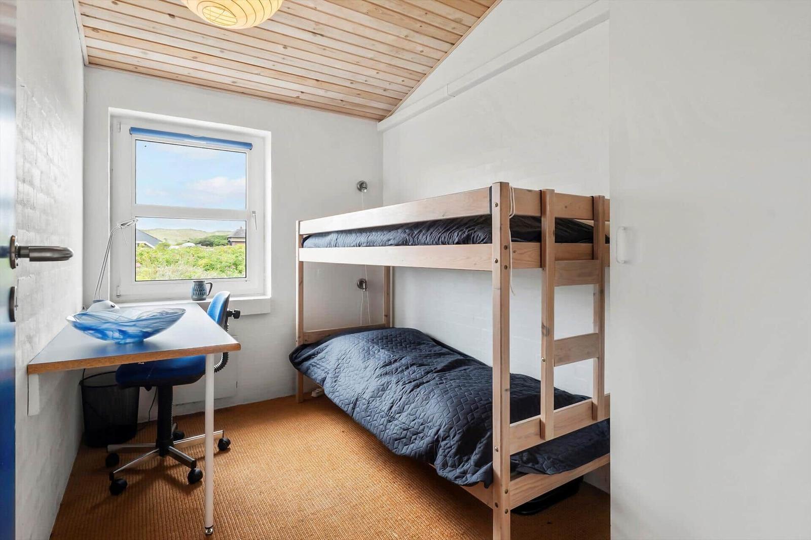 Zimmer mit Doppelstockbett, Schreibtisch und Fenster mit Blick.