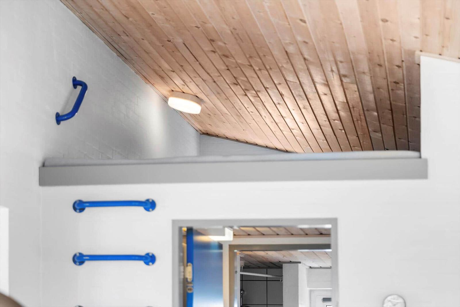 Raum mit Holzdecke und blauen Griffen an der Wand