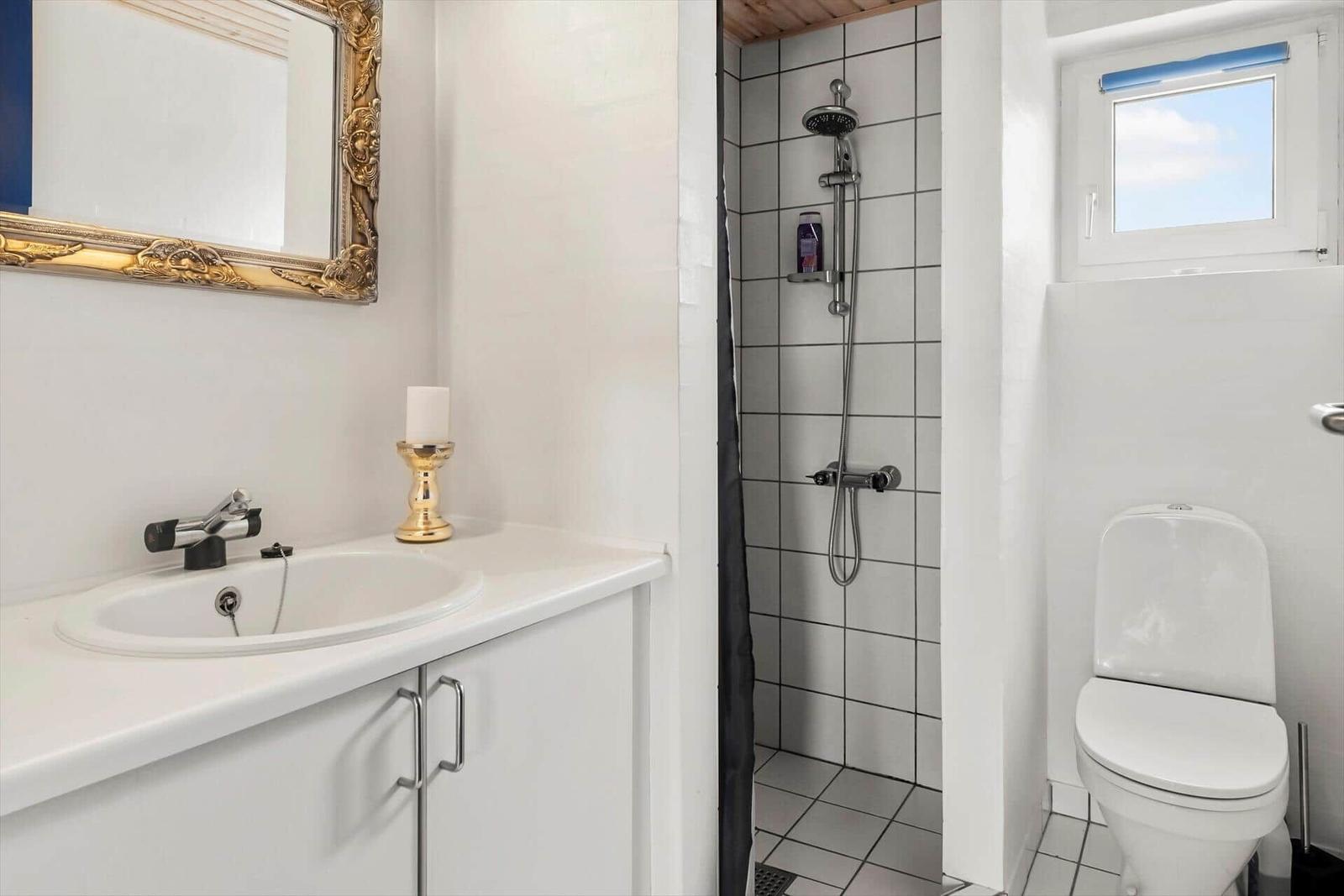 Badezimmer mit Dusche, Toilette und Waschbecken mit Spiegel.