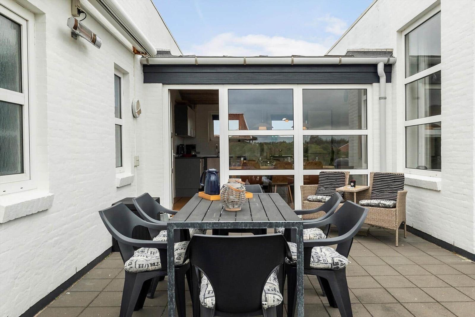 Terrasse mit Tisch, Stühlen und Blick in die Küche.