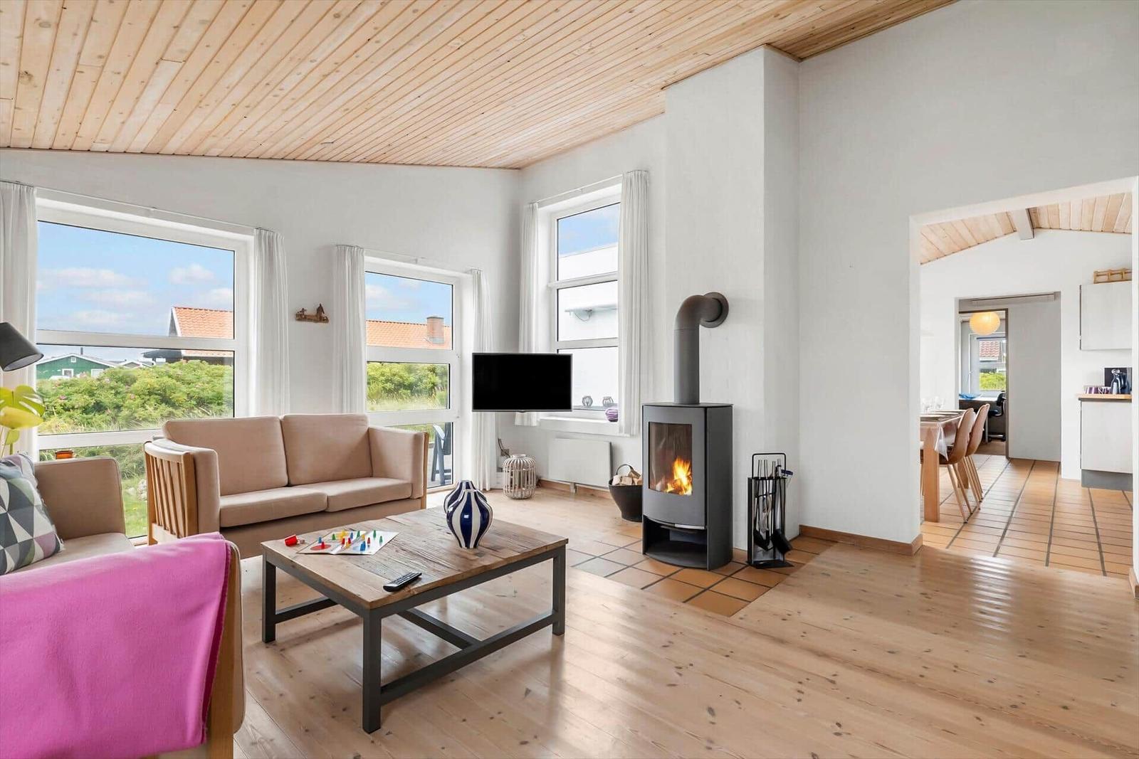 Wohnzimmer mit Kamin, Sofa und Blick auf Garten.