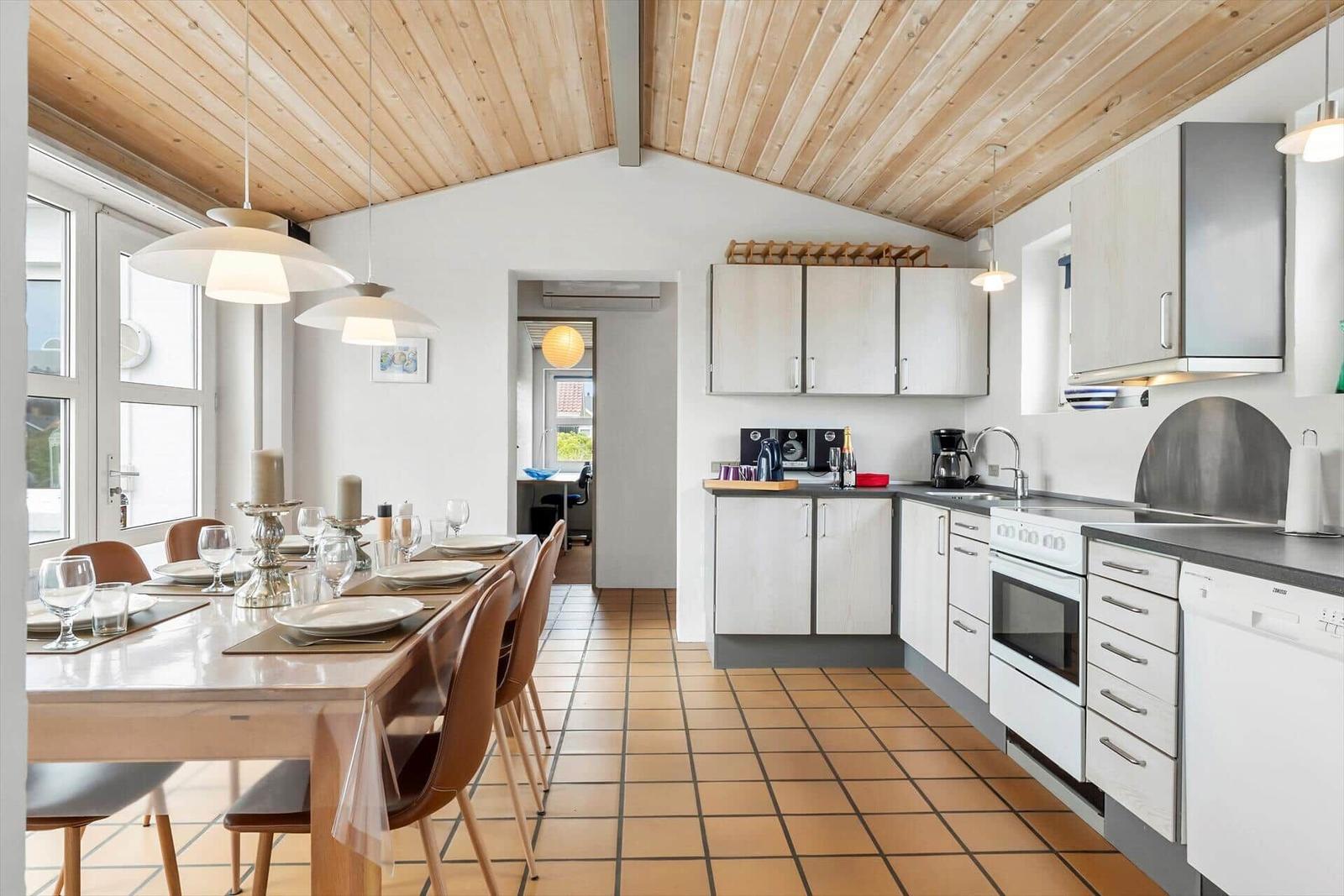 Küche und Essbereich mit Holzdecke, weißen Schränken und Terrakottafußboden.