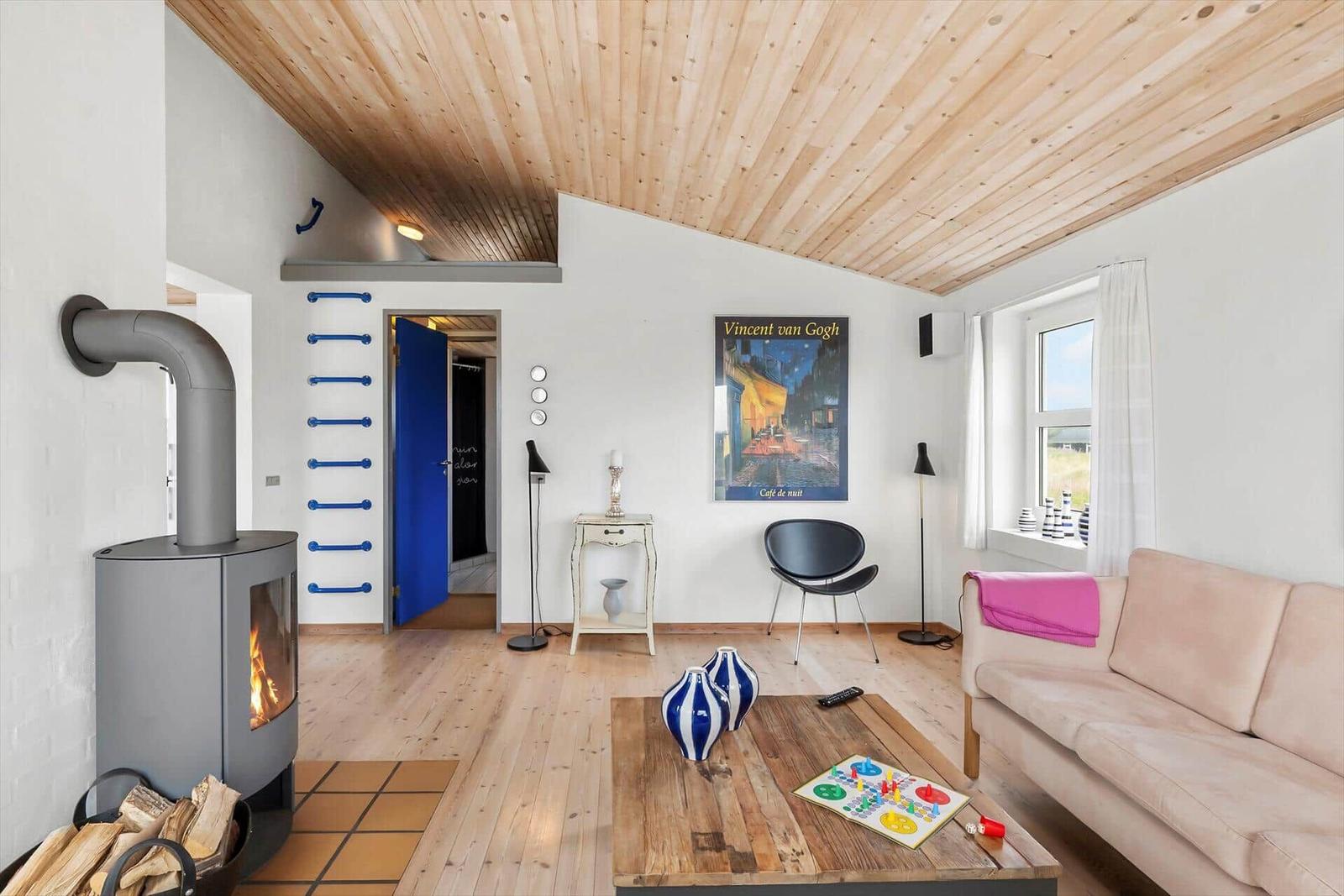 Wohnzimmer mit Holzdecke, Kamin und Sofa. Wandbild Vincent van Gogh.