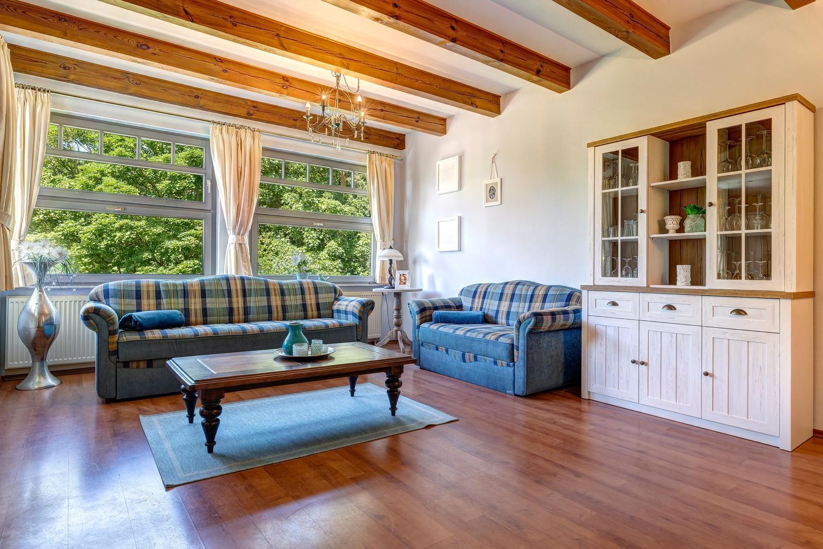 Living room with wooden beams, two sofas, and glass cabinet