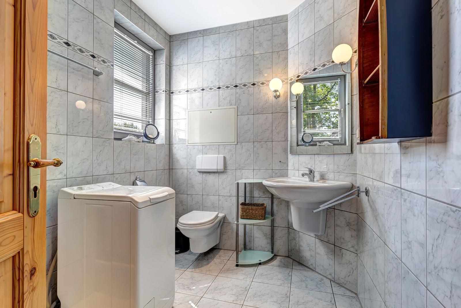 Bathroom with washing machine, toilet, and sink.