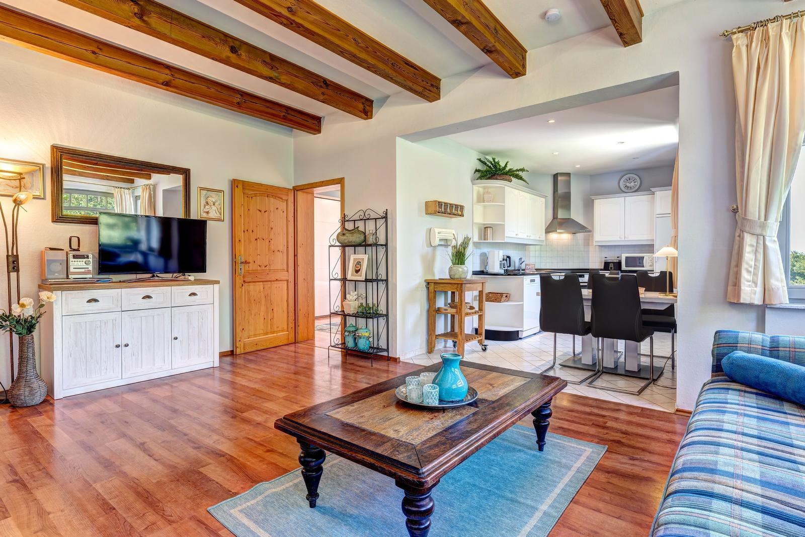 Living and kitchen area with wooden floor and massive beams.