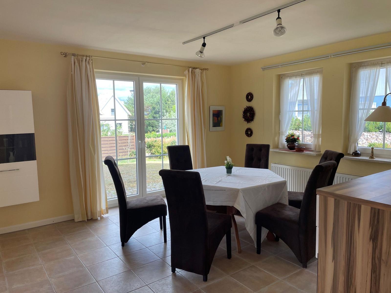 Esszimmer mit Tisch, sechs Stühlen und Blick auf Garten.