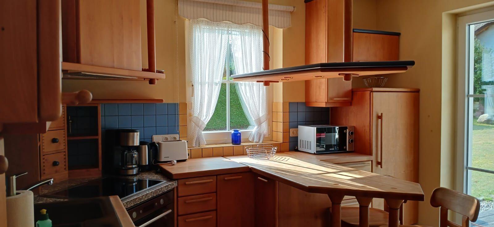 Küche mit Holzmöbeln, Fenster und Mikrowelle