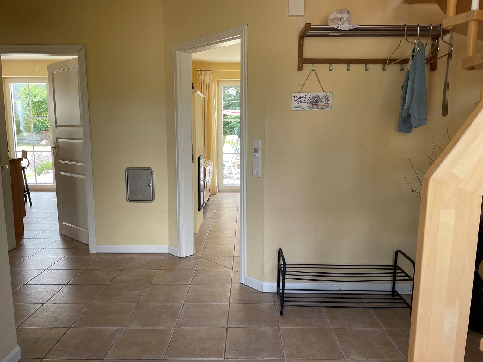 Flur mit Garderobe, Stuhl und Blick in Wohn- und Essbereich.