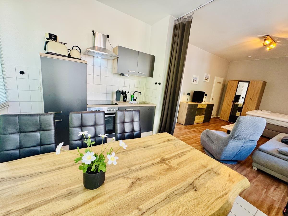 Küche mit Essbereich und Wohnzimmer mit Bett und Sessel