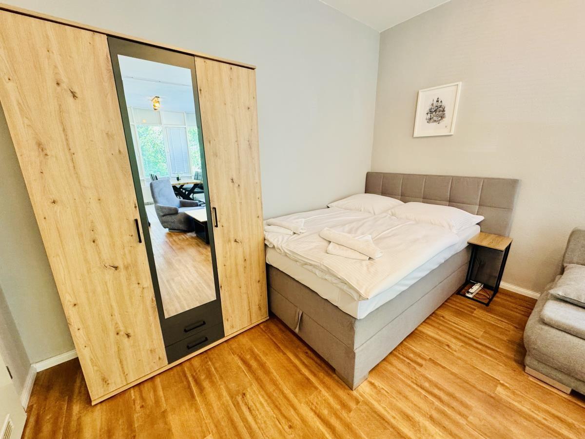 Schlafzimmer mit Bett, Kleiderschrank und Sitzgelegenheit.