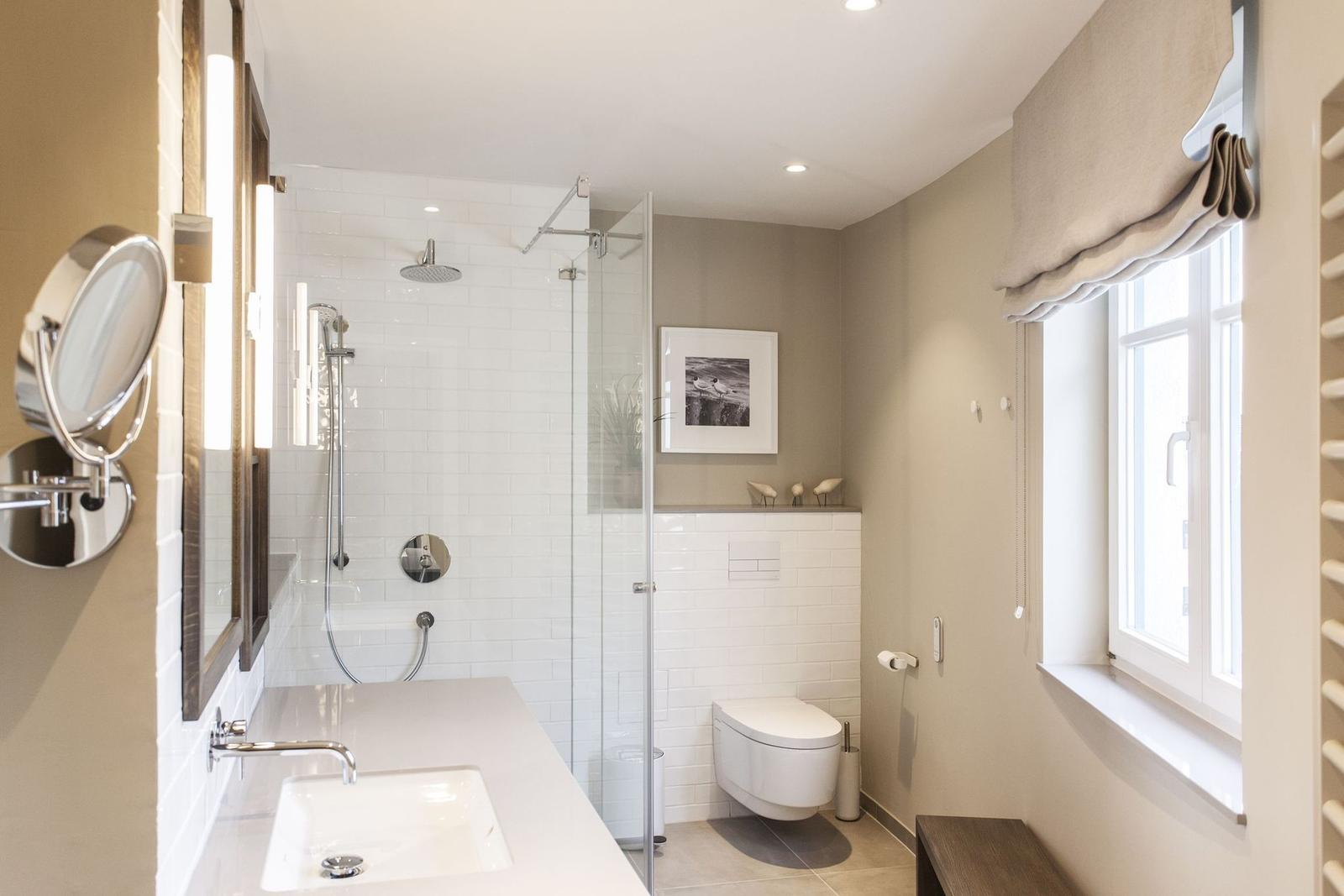 Badezimmer mit Dusche, Waschbecken und Toilette. Fenster mit Rollladen.