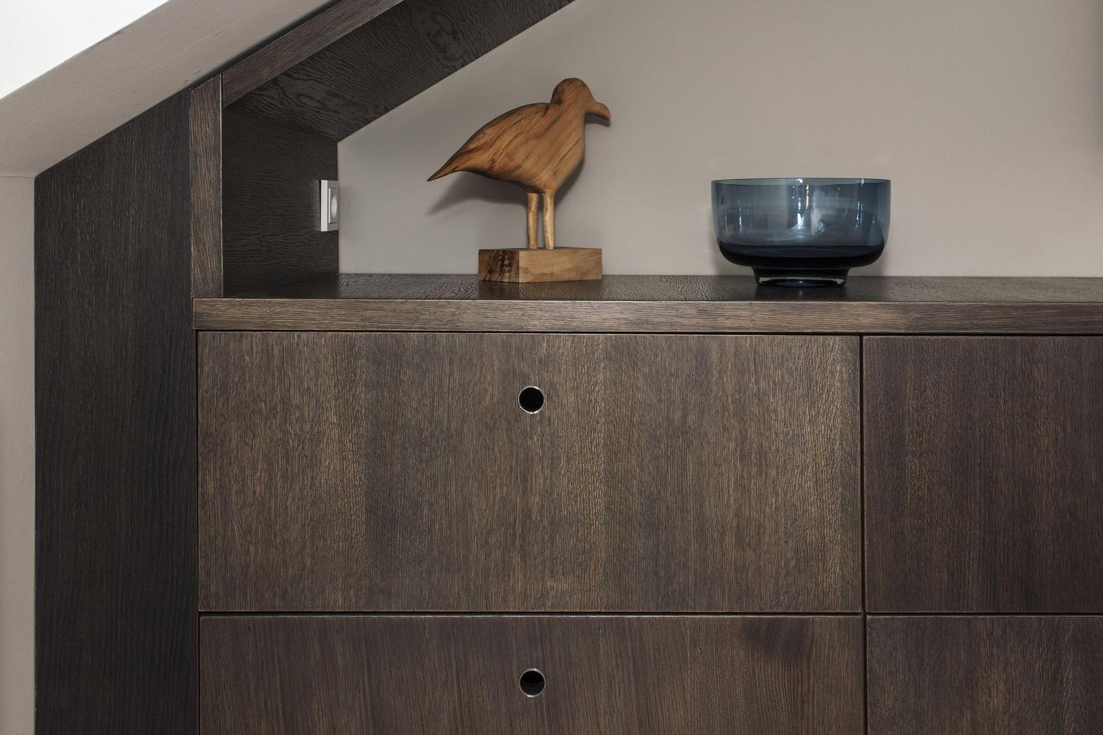 Schrank mit Holzoberfläche, darauf Holzvogel und blaue Schale.