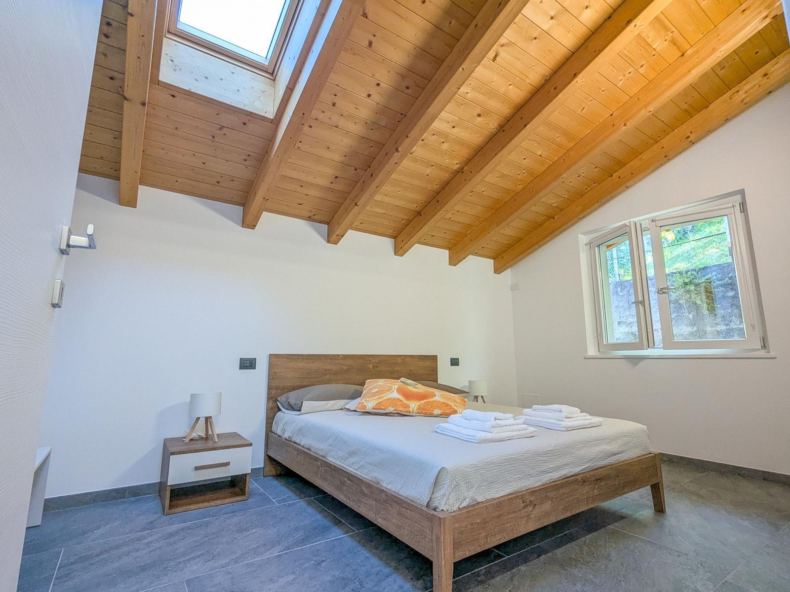 Schlafzimmer mit Holzdecke, Bett und Fenster