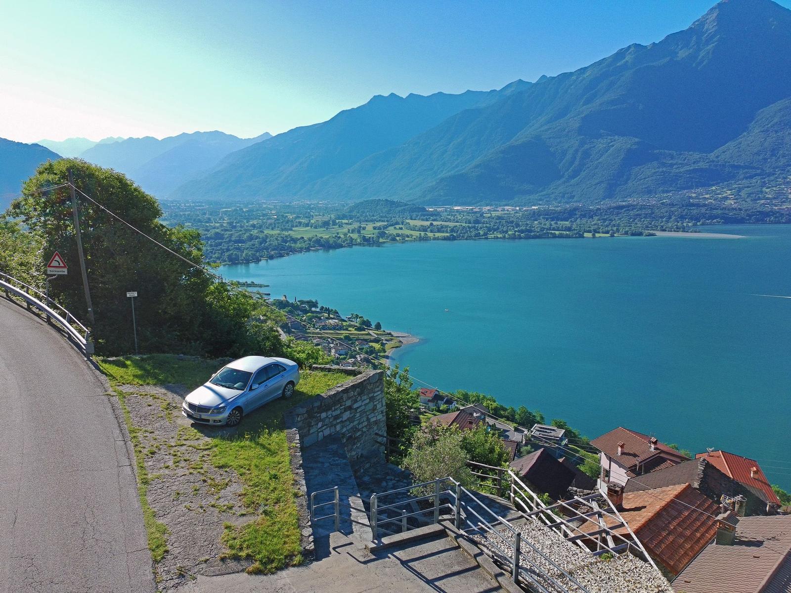 Auto parkt an Straßenrand mit Blick auf See und Berge.