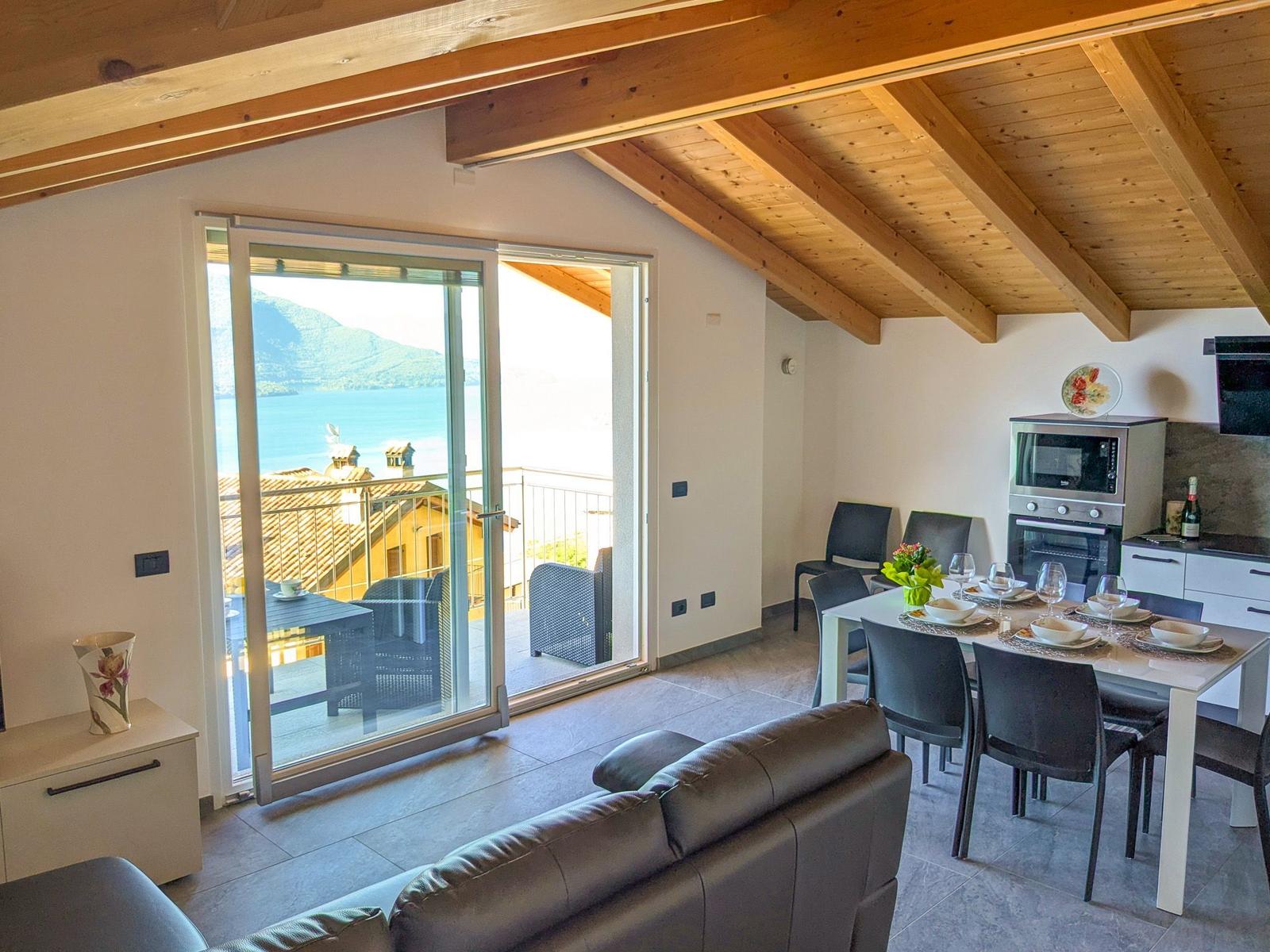 Wohn- und Essbereich mit Blick auf See und Berge. Terrasse mit Sitzmöbeln.