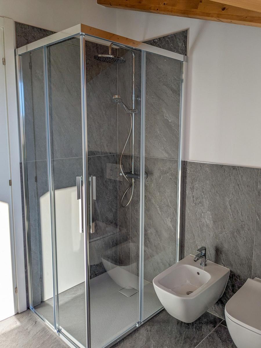 Dusche mit Glaswand, Bidet und Toilette in moderner Badezimmerausstattung.