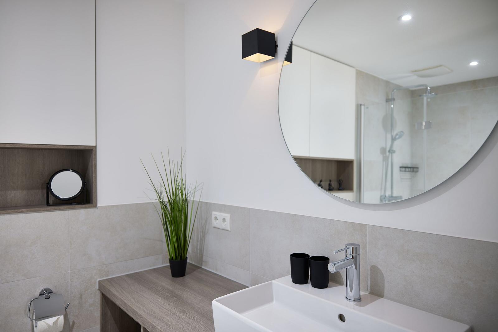 Badezimmer mit Waschbecken, Spiegel und Dusche.