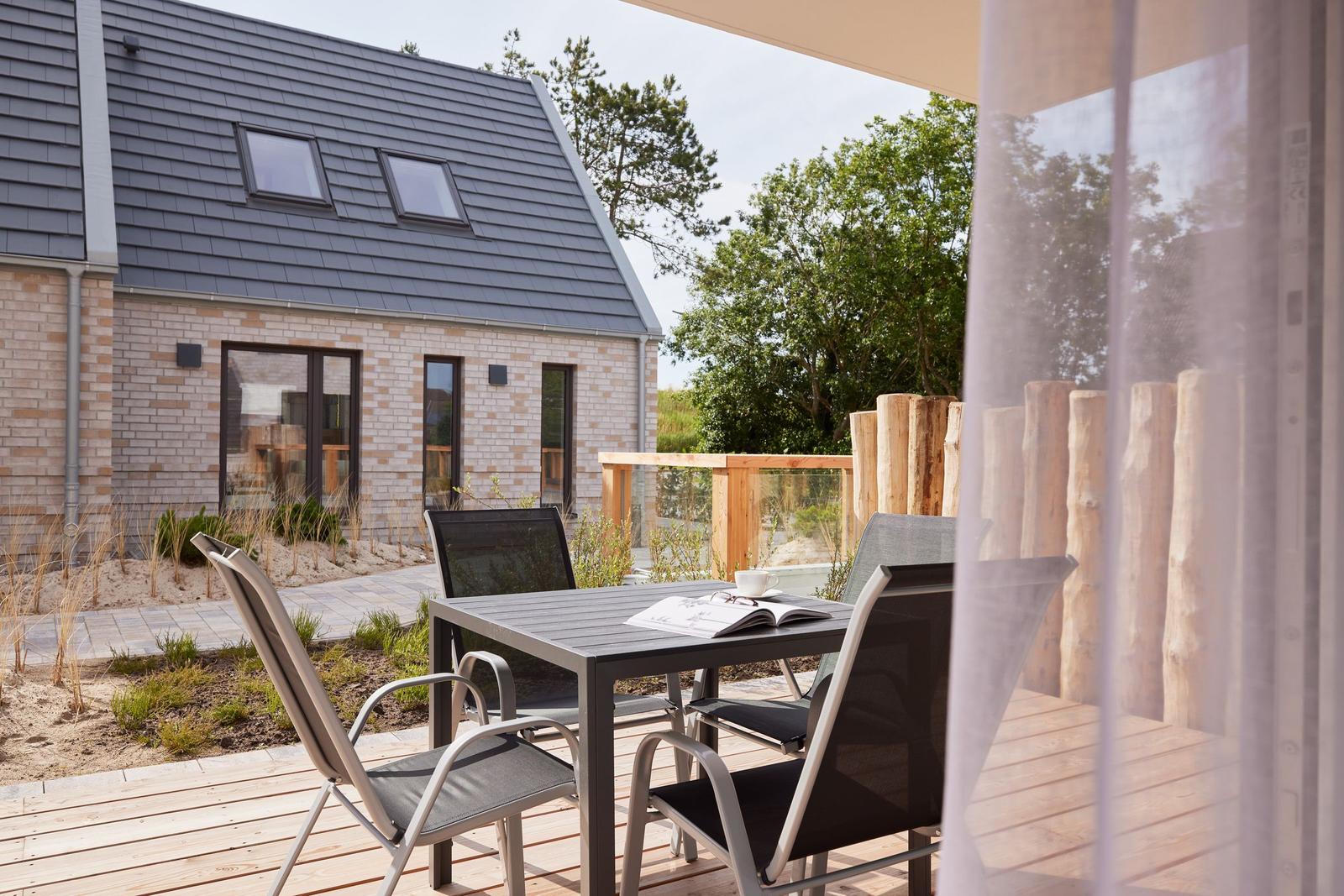 Terrasse mit Tisch und Stühlen, Blick auf modernes Haus mit Dachfenstern.