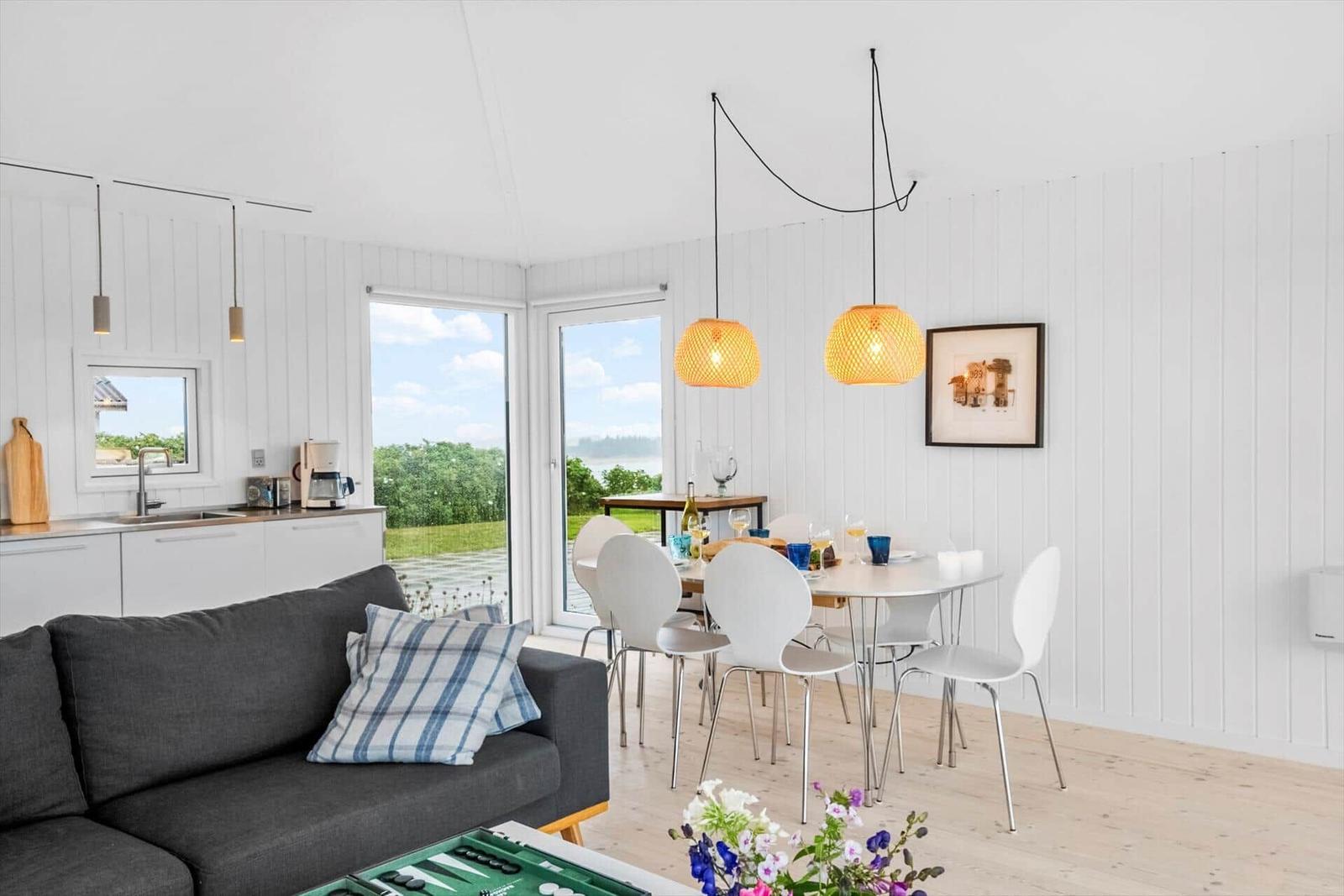 Wohn- und Essbereich mit Küchenzeile, Tisch, Stühlen und Blick auf die Landschaft.